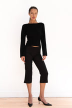 Model wearing black cropped capri trousers with a matching black top and pointed-toe heels
