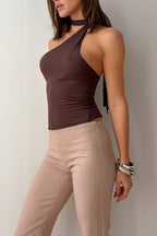Woman wearing a brown halter top and beige pants against a neutral background