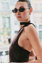 Woman wearing sunglasses and a brown halter top with a blurred background