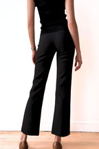 Model wearing a black outfit against a plain background side view
