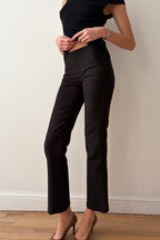 Model wearing a black outfit against a plain background side view
