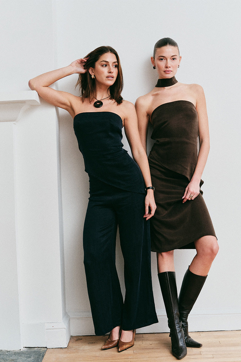 Models wearing strapless outfits against a white wall.