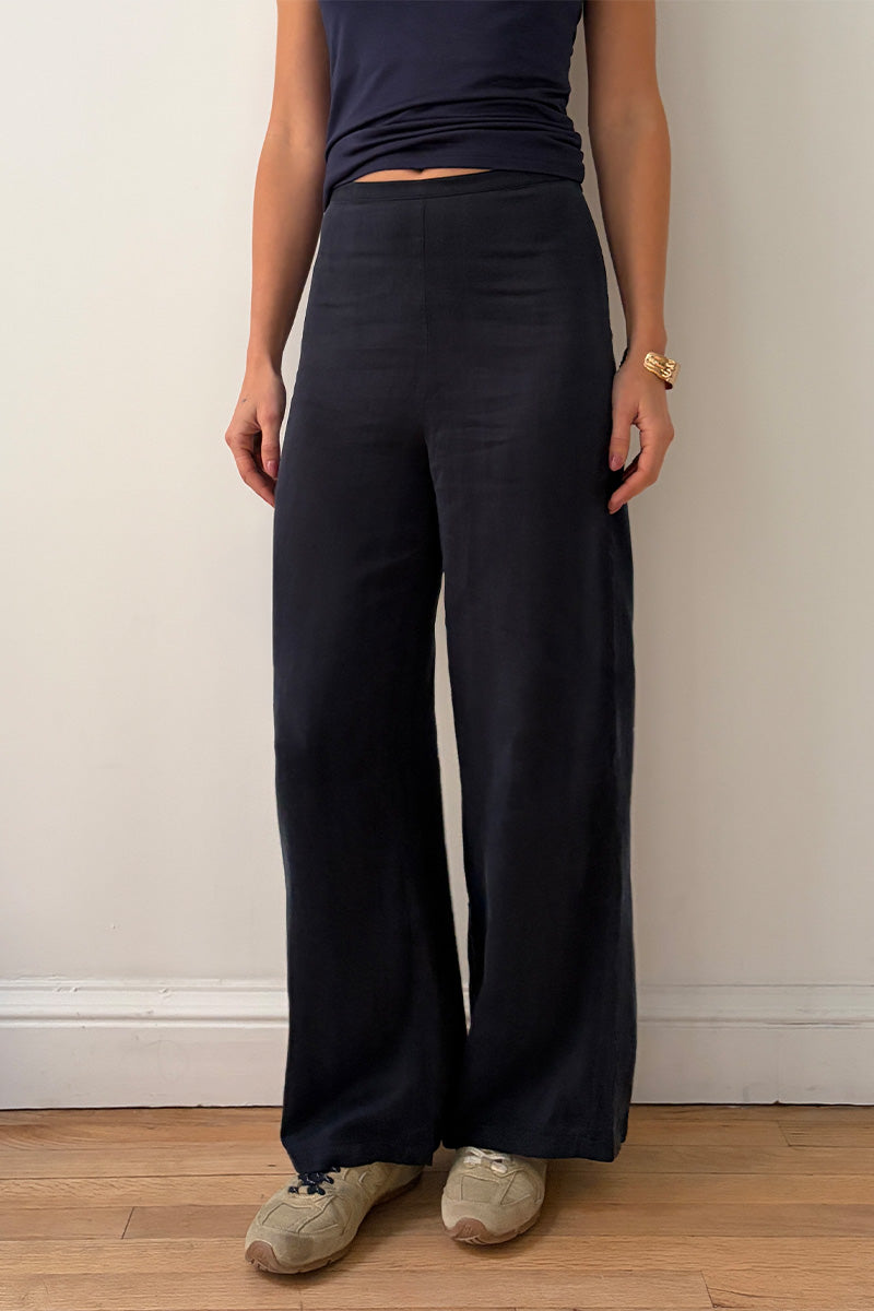 Model wearing navy blue top and wide-leg pants against a plain wall