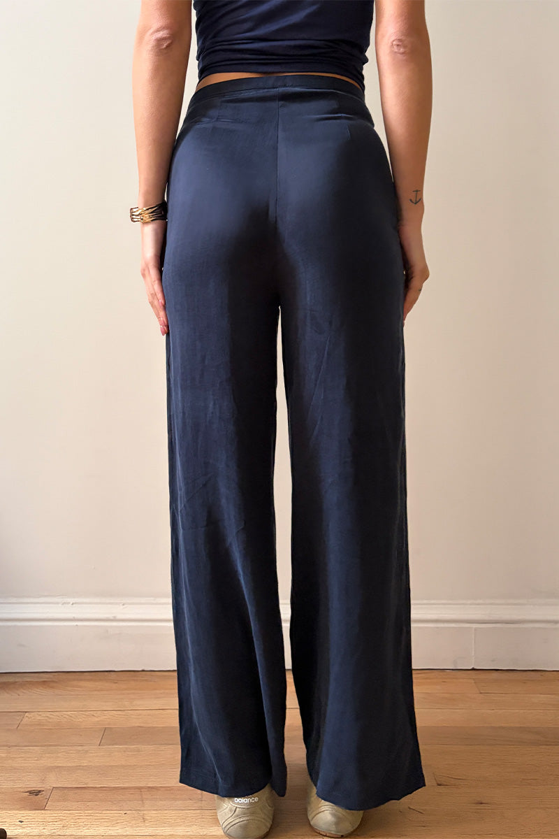 Model wearing navy blue pants standing against a plain wall.