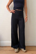 Model wearing navy wide-leg pants and a dark top against a plain background