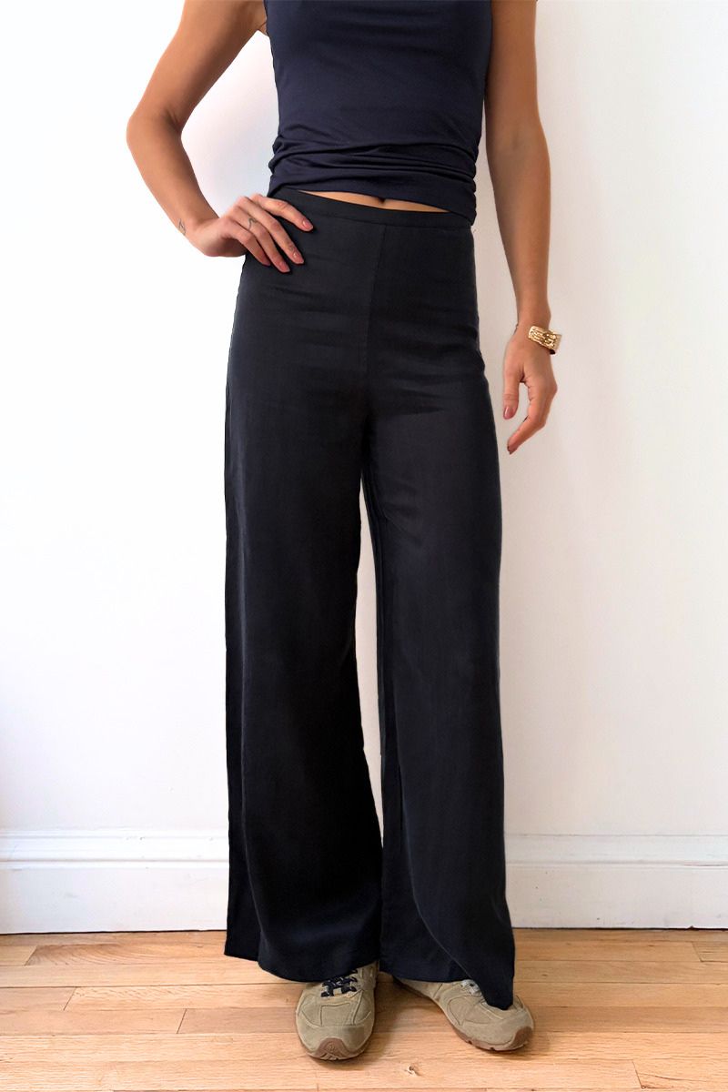 Model wearing navy wide-leg pants and a dark top against a plain background