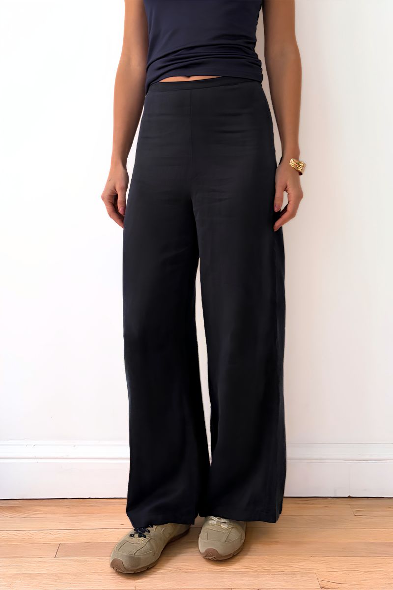 Model wearing navy wide-leg pants and a dark top against a plain background