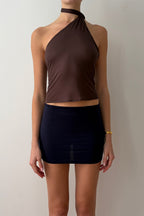 Model wearing a brown halter top and black skirt against a plain background