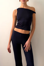 Model wearing a black off-shoulder top and black pants against a plain background