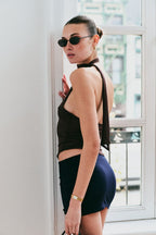 Model wearing a brown halter top and black skirt against a plain background