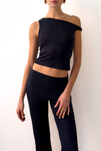 Model wearing a navy off-shoulder top and navy pants against a plain background