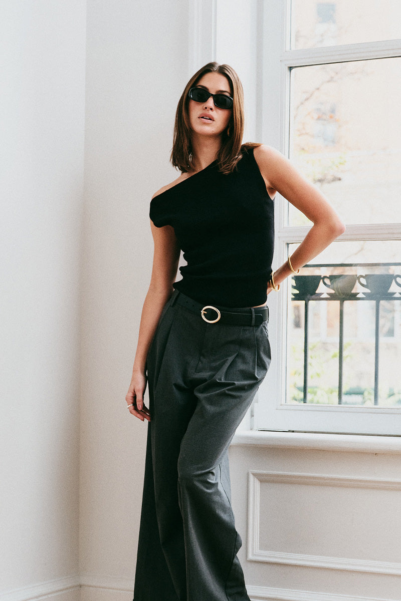Model wearing the Arue Studios Line Trouser in grey, a tailored wide-leg pleated pant with a relaxed drape and high-rise fit.
