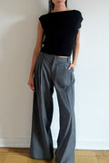 Model wearing the Arue Studios Line Trouser in grey, a tailored wide-leg pleated pant with a relaxed drape and high-rise fit.
