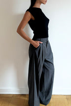 Model wearing the Arue Studios Line Trouser in grey, a tailored wide-leg pleated pant with a relaxed drape and high-rise fit.