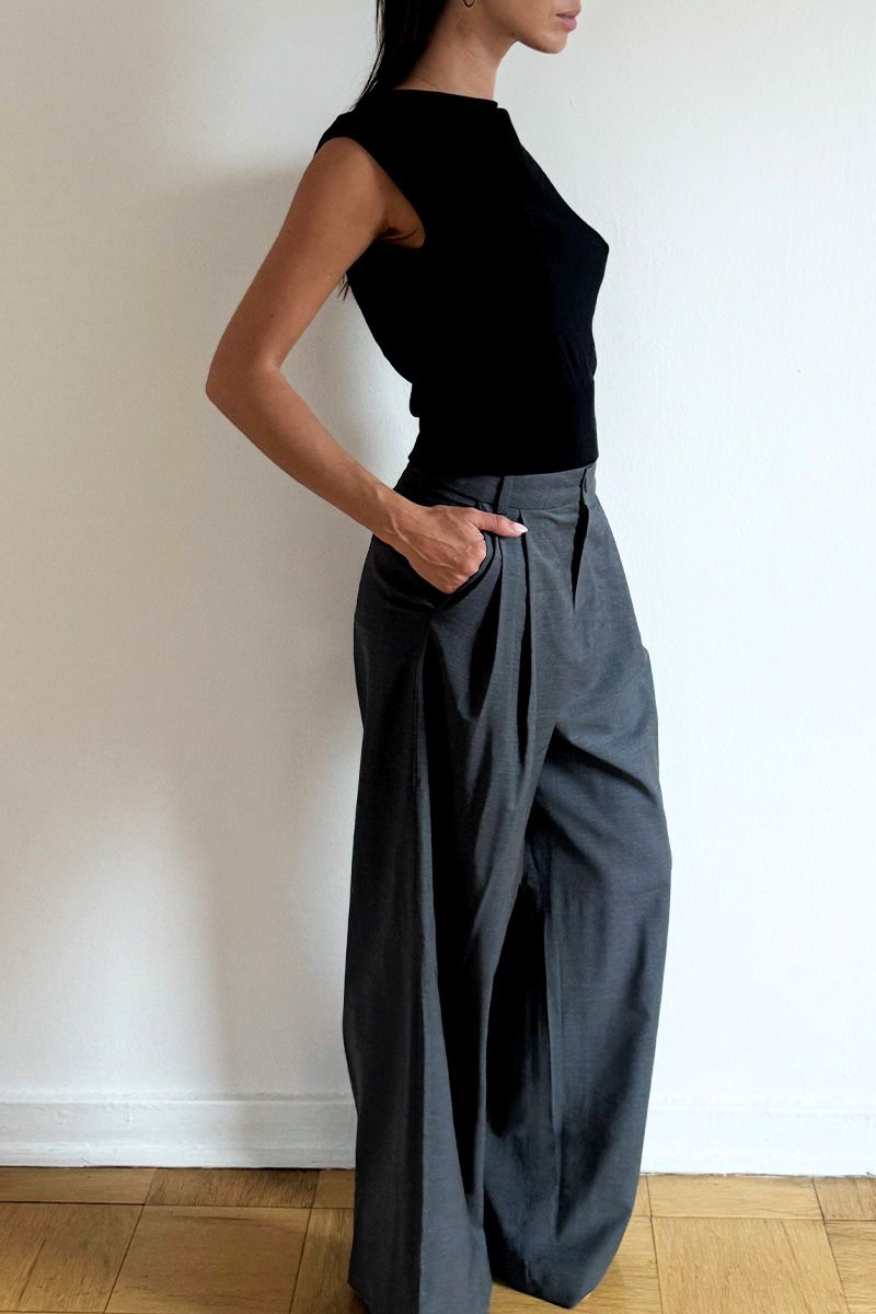 Model wearing the Arue Studios Line Trouser in grey, a tailored wide-leg pleated pant with a relaxed drape and high-rise fit.
