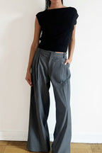 Model wearing the Arue Studios Line Trouser in grey, a tailored wide-leg pleated pant with a relaxed drape and high-rise fit.