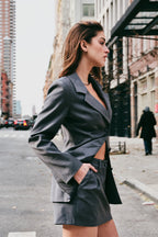 Woman in a gray blazer and skirt standing on a street in New York