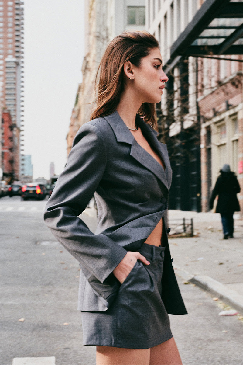 Woman in a gray blazer and skirt standing on a street in New York