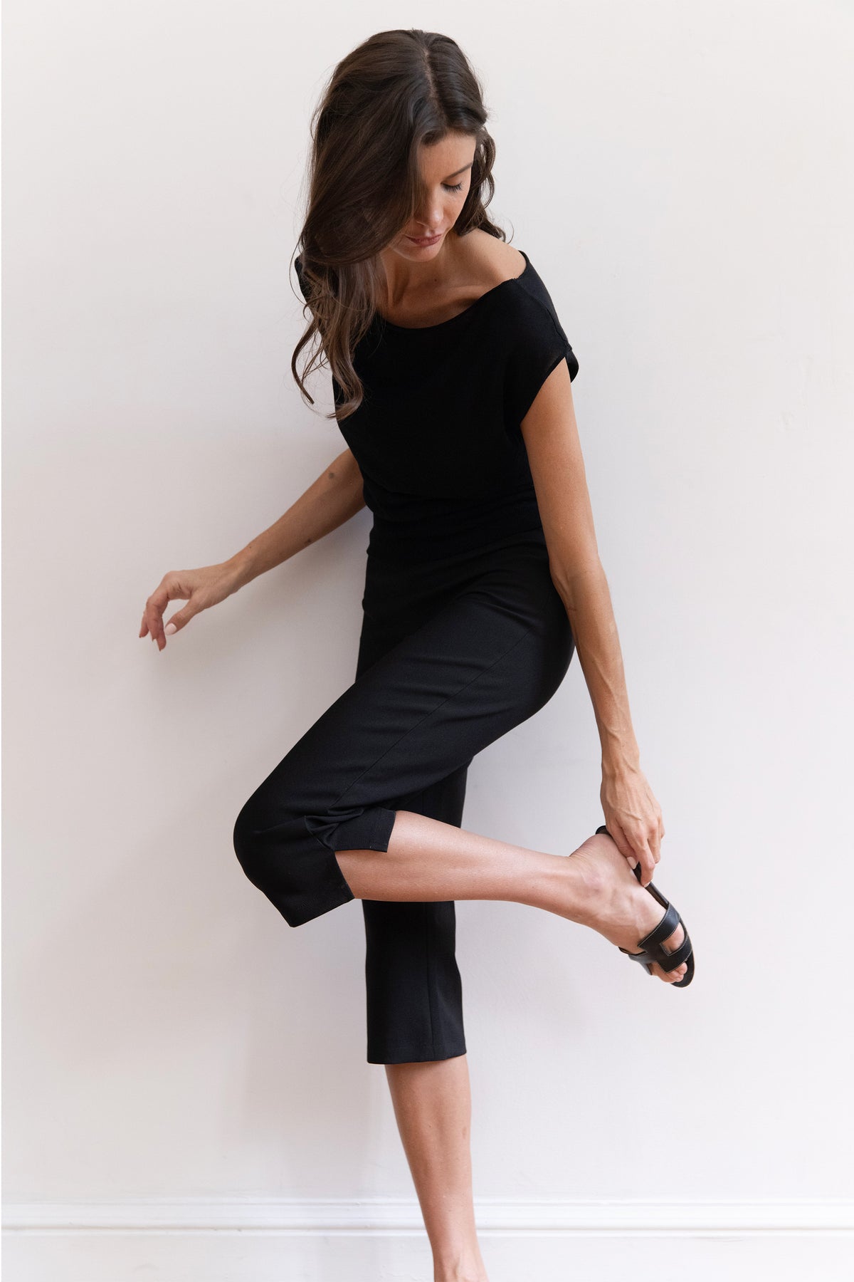 A woman modeling a black off-the-shoulder short-sleeve knit with capri-length legs