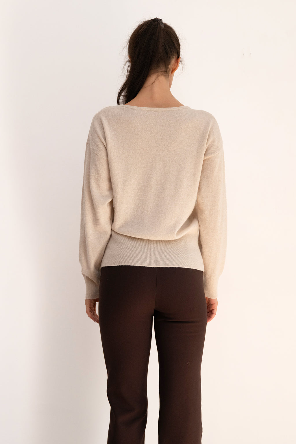 Beige Ease Sweater in a wool and cashmere blend, featuring a V-neckline, relaxed shoulders, and a fitted ribbed waistband.