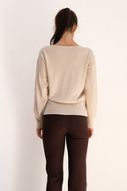 Beige Ease Sweater in a wool and cashmere blend, featuring a V-neckline, relaxed shoulders, and a fitted ribbed waistband.