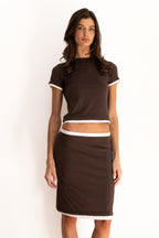 Model wearing the Remi Skirt in espresso brown with ivory contrast waistband and hem, styled low on the waist