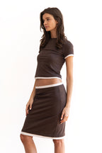 Model wearing the Remi Skirt in espresso brown with ivory contrast waistband and hem, styled low on the waist